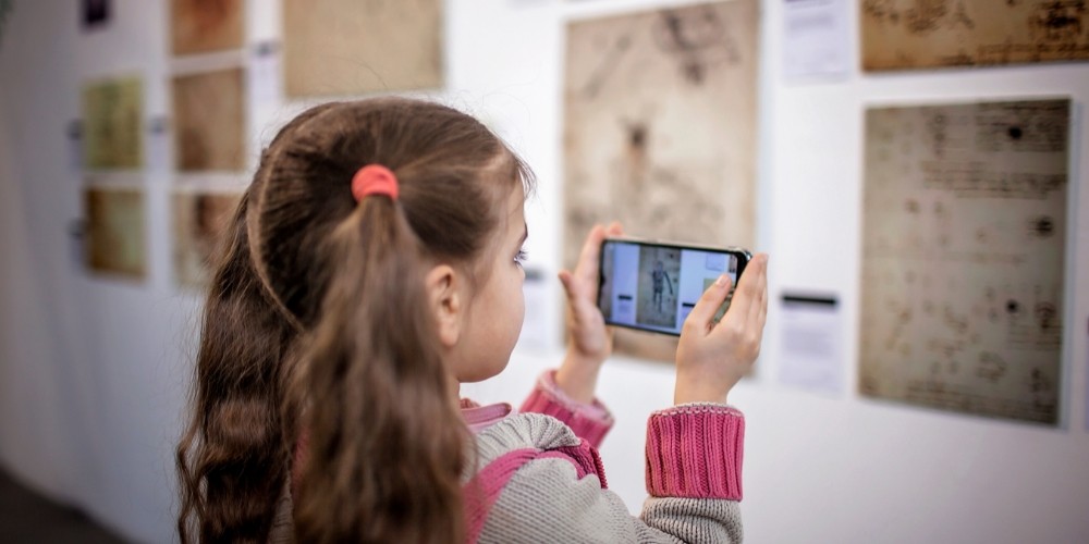 curious-girl-exploring-a-contemporary-art-exhibition-with-augmented-reality-mobile-application